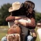 Couple hugging outdoors with leather backpack.