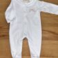 White baby onesie on wooden surface.