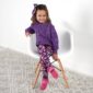 Child in purple sweater and floral leggings, sitting.