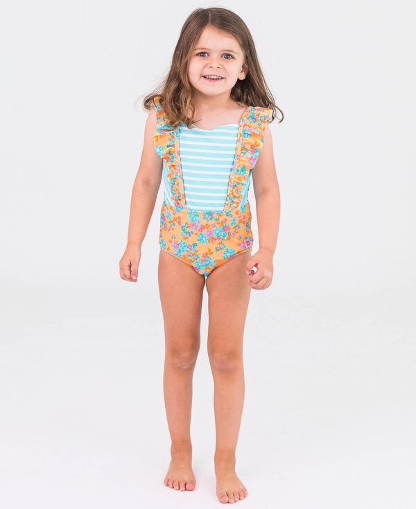 Child wearing floral one-piece swimsuit, smiling.