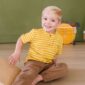 Smiling child in yellow striped shirt sitting indoors.