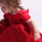 Child in red dress with curly hair.