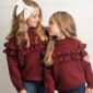 Two girls in matching burgundy sweaters hugging.