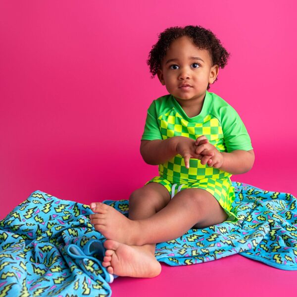 gigi and max brad green neon swim set Child in checkered outfit on colorful blanket.