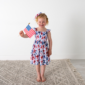 Child holding American flag in festive dress.