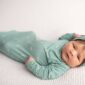 Newborn baby in green swaddle and headband