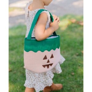 Child carrying pumpkin-themed trick-or-treat bag outside.