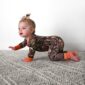 Baby in camouflage crawling on carpet