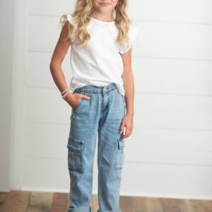 Smiling child in casual outfit on wooden floor.