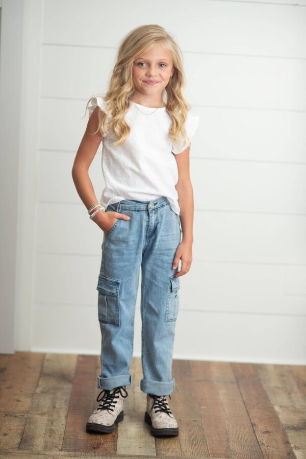 Smiling child in casual outfit on wooden floor.