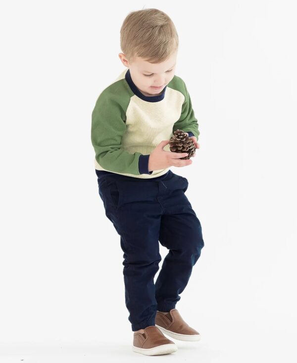 Child holding a pine cone, wearing casual clothes.