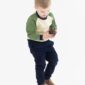 Child holding a pine cone, wearing casual clothes.