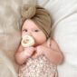 Baby with pacifier wearing floral dress and turban.