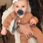Baby with pacifier and headband held by parent.