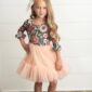 Child wearing floral dress with soft pink skirt.
