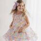 Smiling girl twirls in colorful dress indoors.