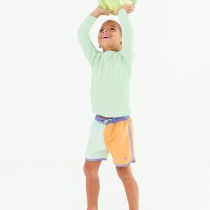 Smiling child holding inflatable ball overhead.