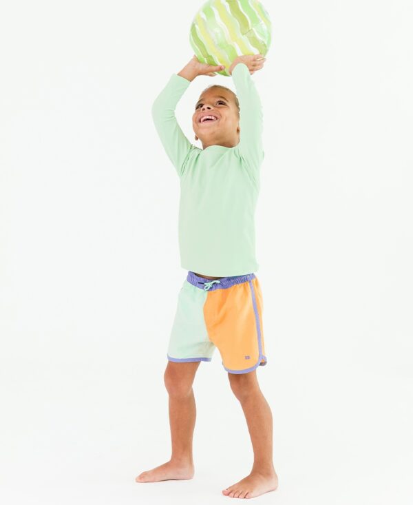 Smiling child holding inflatable ball overhead.