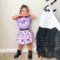 Child in Halloween costume next to ghost decoration.
