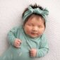 Sleeping baby in teal outfit with headband.