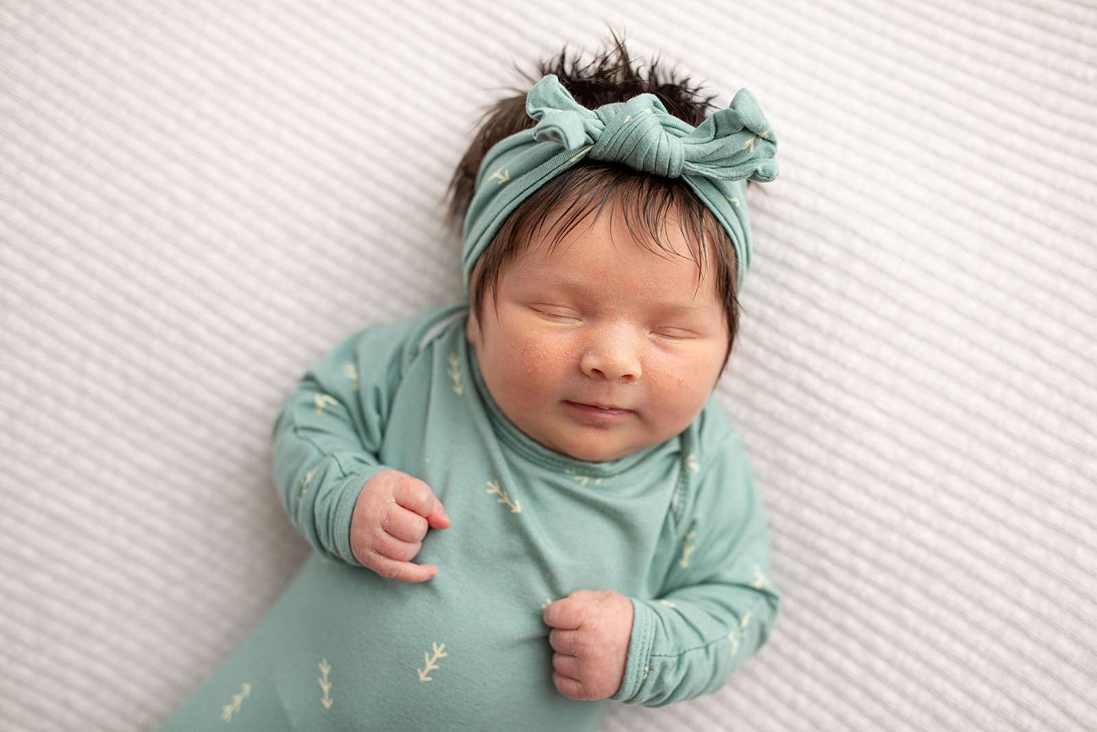 Sleeping baby in teal outfit with headband.