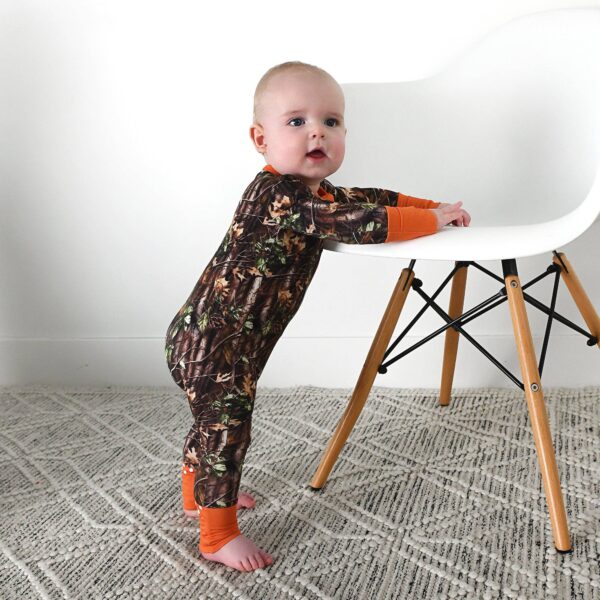 gigi and max hunter camo zip sleepies little bamboo baby outfit Baby in camouflage onesie standing by chair