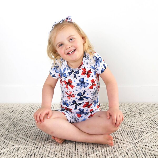 gigi and max eleanor bow clip bow 4th of july hair accessory Smiling child in butterfly-patterned outfit.