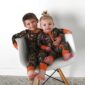 Smiling children in camouflage pajamas on chair.