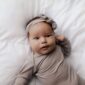 Baby lying on white blanket in gray outfit.