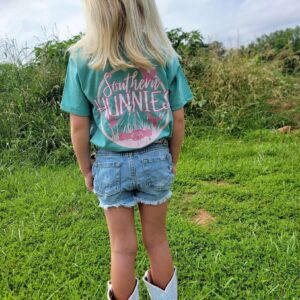 Child wearing Southern Hunnies shirt outdoors in grass.