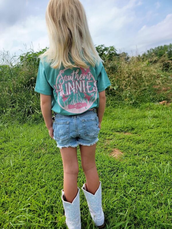 Child wearing Southern Hunnies shirt outdoors in grass.
