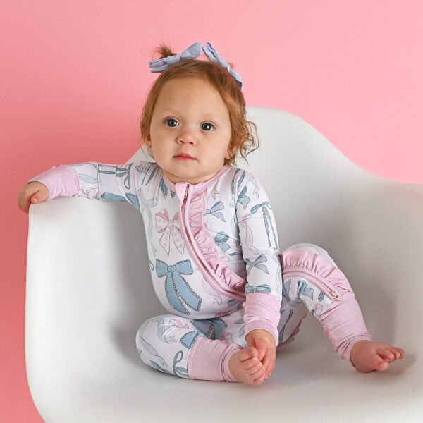 gigi and max samantha bows ruffle zip bamboo sleeplies little outfit Baby in bow-patterned pajamas on white chair