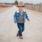Child in denim and cowboy hat walking outside