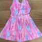 Colorful pink toddler dress on wooden surface.
