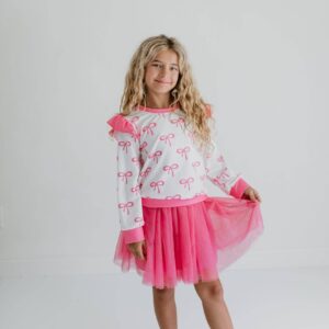 Girl wearing pink bow-patterned outfit.