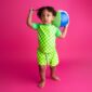 Child in green checkered outfit holding beach ball.