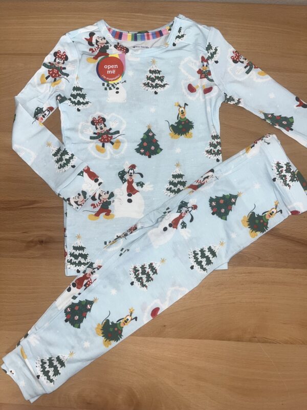 Disney-themed pajamas with Christmas patterns on wood surface.