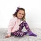 Girl in floral leggings and pink sweater smiling.