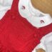 Red dress with Santa details, wooden background.