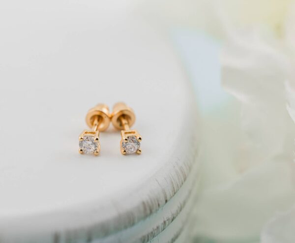 cherished moments kids 14k gold clear cz earrings Gold diamond stud earrings on white surface