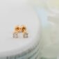 Gold diamond stud earrings on white surface