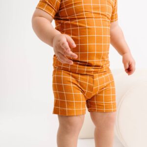 Child wearing orange checkered clothes, white background