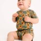 Baby wearing sunflower-patterned outfit, smiling happily.