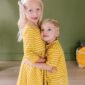 Children in yellow striped outfits hugging each other.