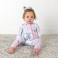 Baby in bow-patterned pajamas sitting on carpet.