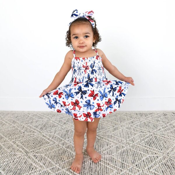 gigi and max eleanor bow clip bow 4th of july hair accessory Toddler in floral dress and headband posing indoors.