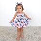 Toddler in floral dress and headband posing indoors.