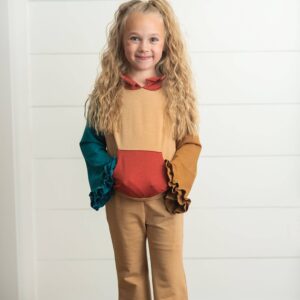 Child in colorful ruffled outfit smiling indoors.