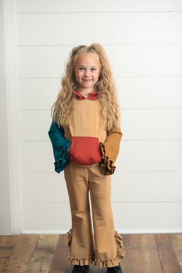 Child in colorful ruffled outfit smiling indoors.