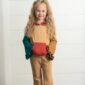 Child in colorful ruffled outfit smiling indoors.
